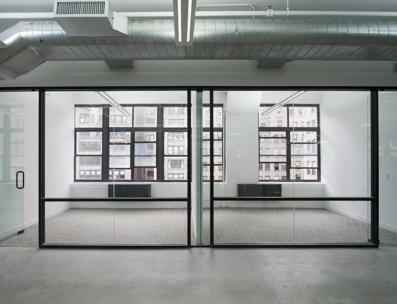 Completed private offices with full-height glass doors and neutral carpet