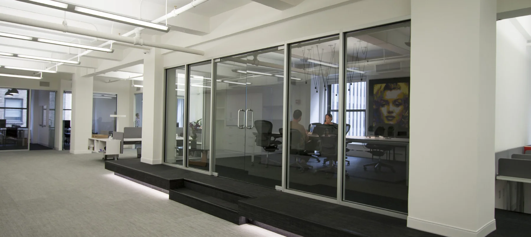 Black-framed conference room beside an open commercial workspace