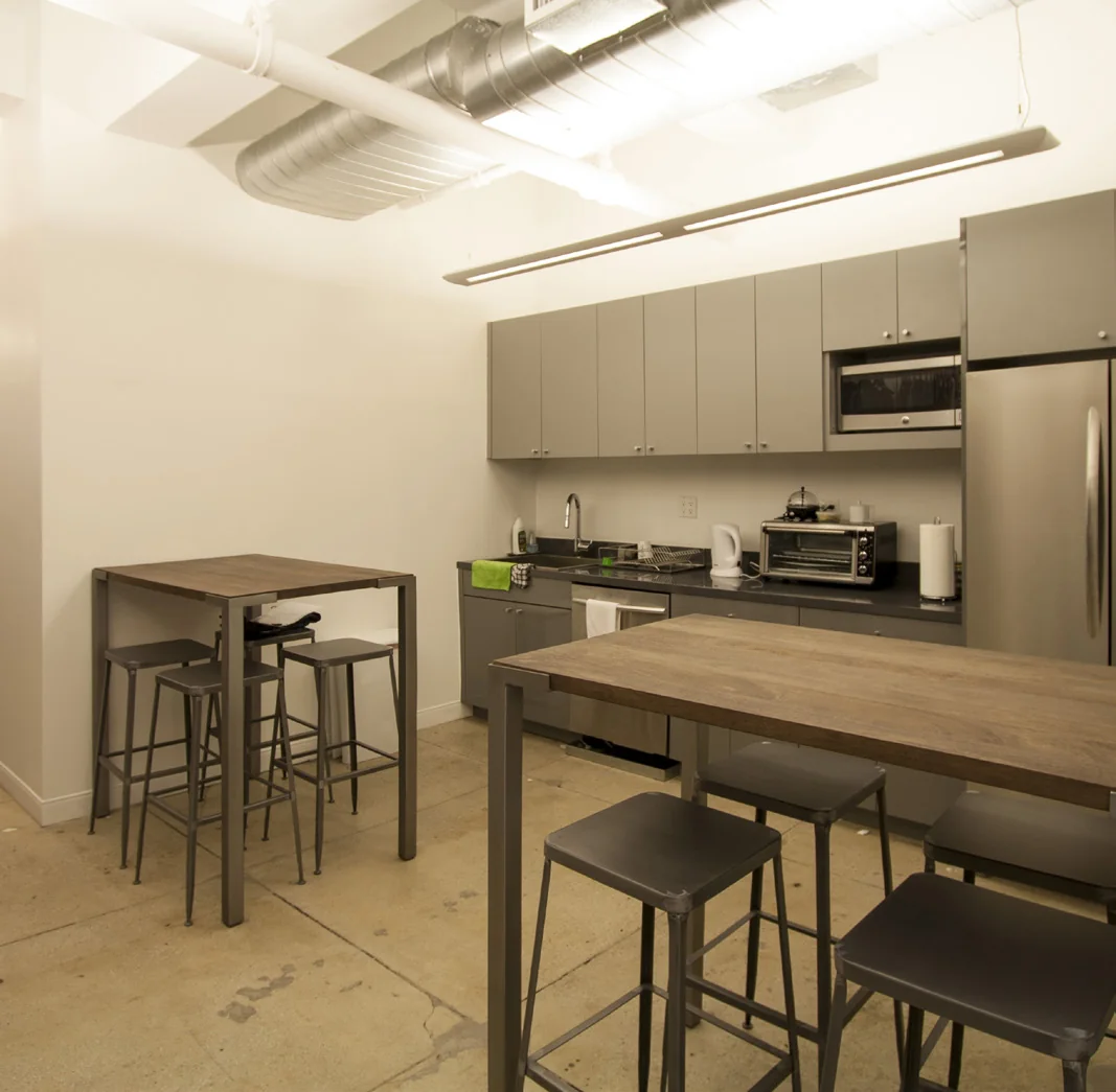 Compact workplace pantry with gray cabinetry and wood tables