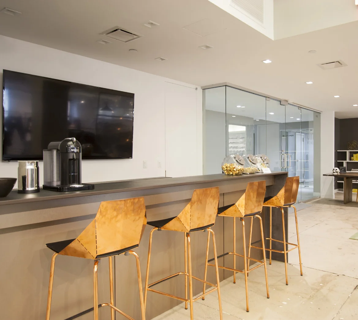 Commercial pantry with integrated screens, bar seating, and glass office front