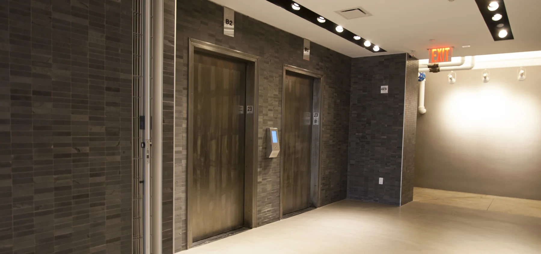 Renovated elevator vestibule with dark tile and architectural lighting