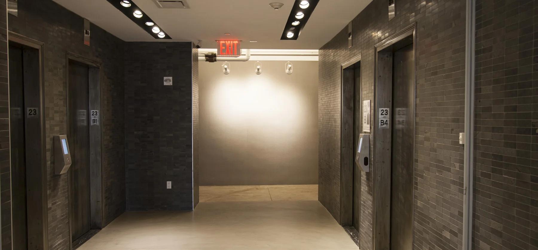 Symmetrical elevator lobby with dark finishes and gallery lighting
